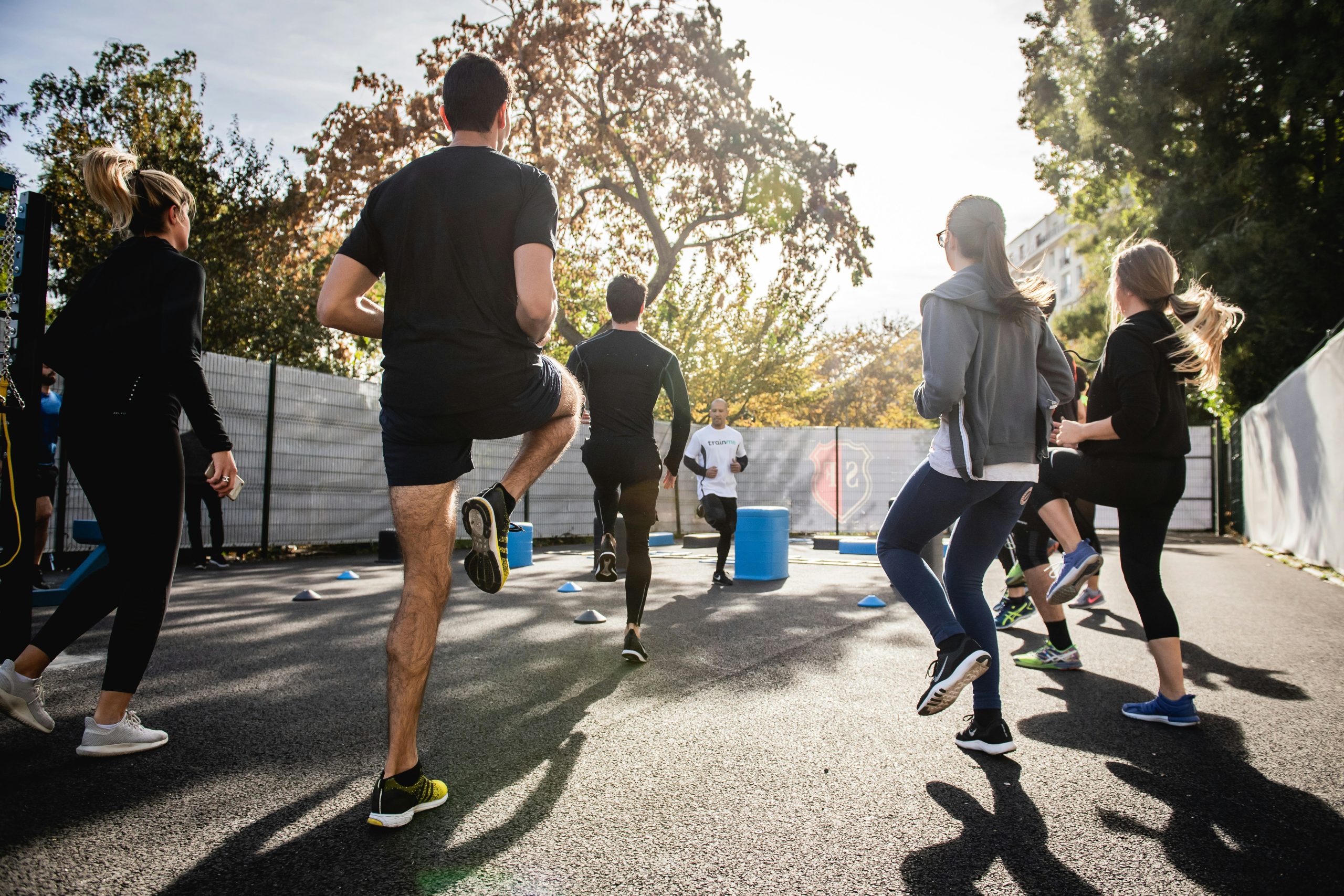 A group of people exercising outdoors together, engaging in fitness training on a sunny day.